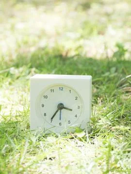White simple clock on lawn yard, 3:35 three thirty five Stock Photos