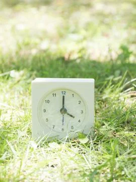 White simple clock on lawn yard, 4:00 four o'clock Stock Photos