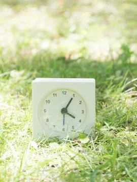 White simple clock on lawn yard, 4:05 four five Stock Photos
