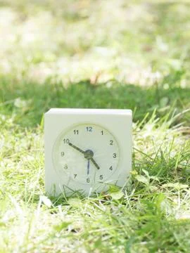 White simple clock on lawn yard, 4:50 four fifty Stock Photos