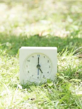 White simple clock on lawn yard, 5:00 five o'clock Stock Photos