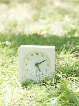 White simple clock on lawn yard, 5:10 five ten Stock Photos