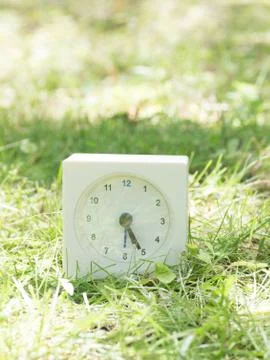 White simple clock on lawn yard, 5:25 five twenty five Stock Photos