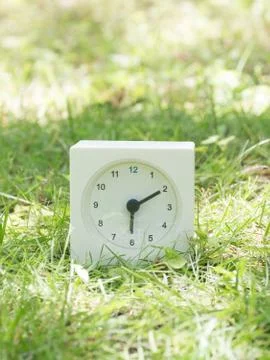 White simple clock on lawn yard, 6:10 six ten Stock Photos