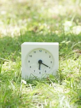 White simple clock on lawn yard, 6:20 six twenty Stock Photos