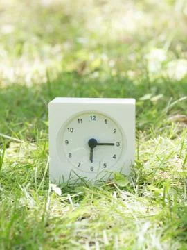 White simple clock on lawn yard, 6:15 six fifteen Stock Photos