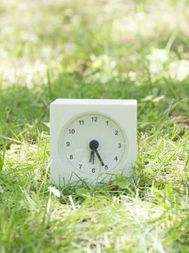 White simple clock on lawn yard, 6:25 six twenty five Stock Photos
