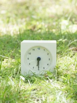White simple clock on lawn yard, 6:30 six thirty half Stock Photos
