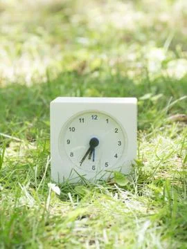 White simple clock on lawn yard, 6:35 six thirty five Stock Photos
