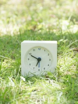 White simple clock on lawn yard, 6:50 six fifty Stock Photos