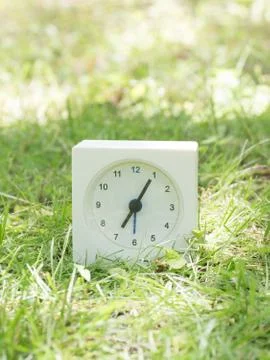 White simple clock on lawn yard, 7:05 seven five Stock Photos