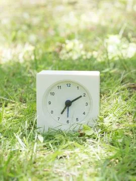 White simple clock on lawn yard, 7:10 seven ten Stock Photos