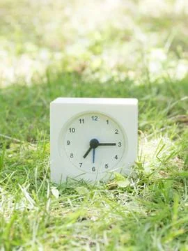 White simple clock on lawn yard, 7:15 seven fifteen Stock Photos