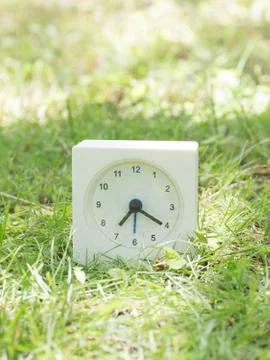 White simple clock on lawn yard, 7:20 seven twenty Stock Photos