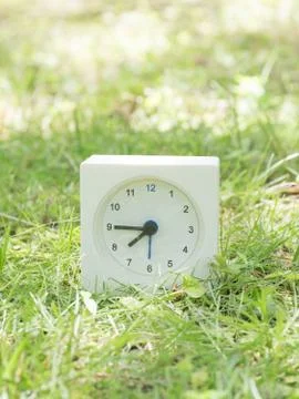 White simple clock on lawn yard, 7:45 seven forty five Stock Photos