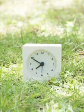 White simple clock on lawn yard, 7:50 seven fifty Stock Photos
