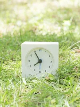 White simple clock on lawn yard, 7:55 seven fifty five Stock Photos