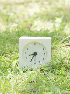 White simple clock on lawn yard, 8:35 eight thirty five Stock Photos