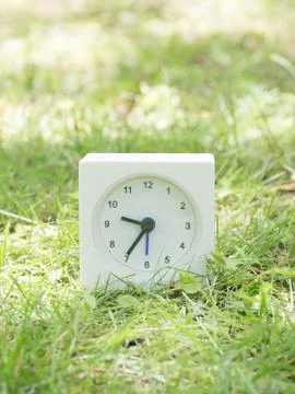 White simple clock on lawn yard, 9:35 nine thirty five Stock Photos