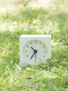 White simple clock on lawn yard, 10:35 ten thirty five Stock Photos