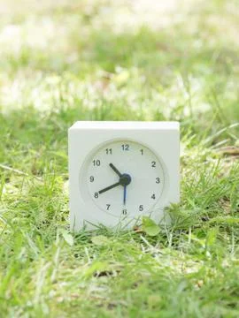 White simple clock on lawn yard, 10:40 ten forty Stock Photos