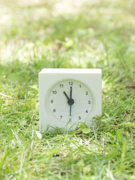 White simple clock on lawn yard, 11:00 eleven o'clock Stock Photos