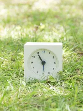 White simple clock on lawn yard, 10:55 ten fifty five Stock Photos