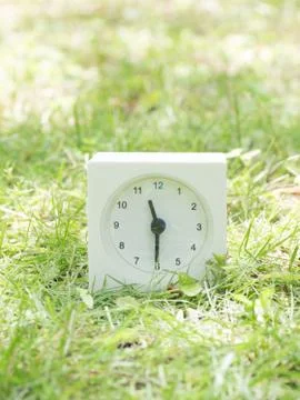 White simple clock on lawn yard, 11:30 eleven thirty half Stock Photos