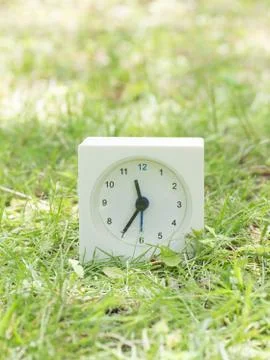 White simple clock on lawn yard, 11:35 eleven thirty five Stock Photos