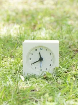 White simple clock on lawn yard, 11:40 eleven forty Stock Photos