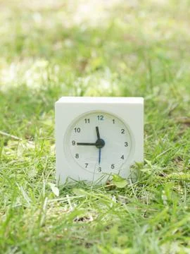 White simple clock on lawn yard, 11:45 eleven forty five Stock Photos