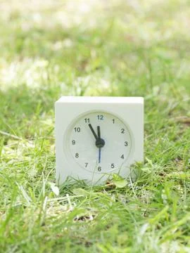 White simple clock on lawn yard, 11:55 eleven fifty five Stock Photos