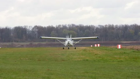 A white single-engine light plane slowly drives across the grass. Video stock 204159233
