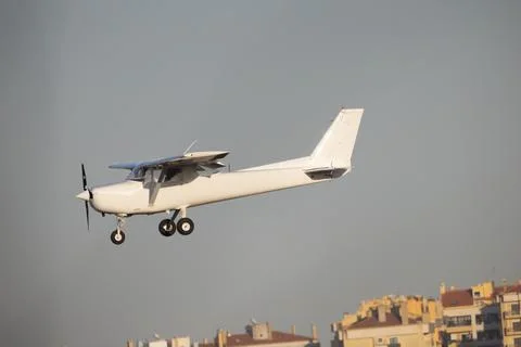 White single engine propeller aircraft flying in blue sky Stock Photos