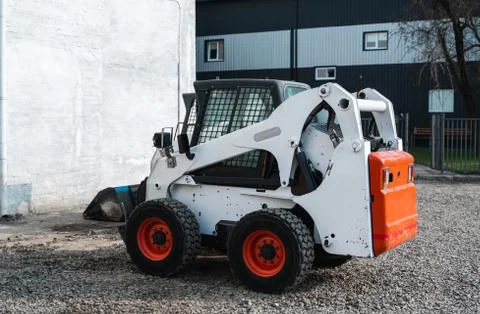White skid steer loader at a construction site waiting of work. Industrial Stock Photos