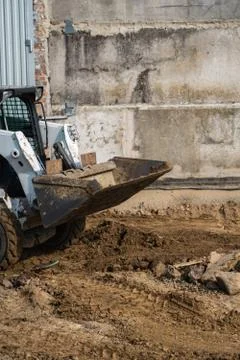 White skid steer loader at a construction site working with a soil. Industrial Stock Photos