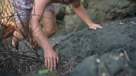 A white-skinned man with a pleasant appearance and a naked torso climbs a rock. Stock Footage 234021499