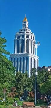 White skyscraper with trees below against a blue sky Stock Photos