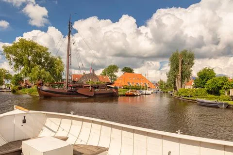 White sloop in front of an old sailing boat in a canal in the Dutch village o Stock Photos