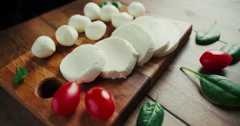 White small mozzarella cheese balls, spinach leaves on wooden board. Dolly-in Stock Footage 147451332