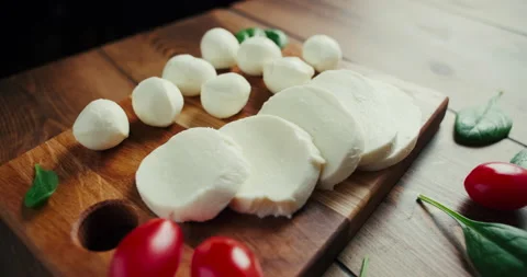 White small mozzarella cheese balls, spinach leaves on wooden board. Dolly-in Stock Footage 147560585