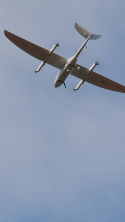 White smart drone in the shape of an airplane flies and films in the clear blue Stock Footage 314307210