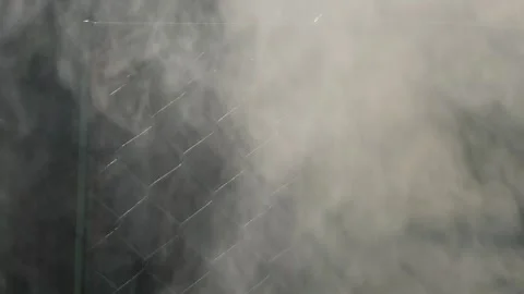 White smoke billowing in front of chain link fence Видео 337392566