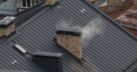 White smoke billows from a brick chimney on a dark metal roof. Stock Footage 320169874