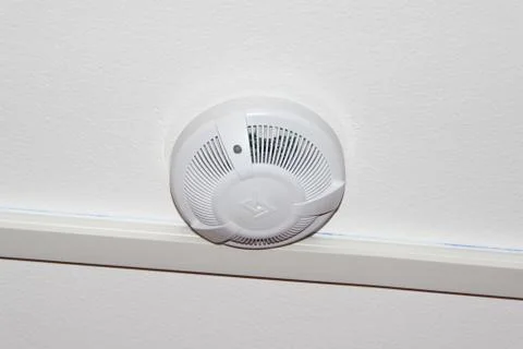White smoke detector on the ceiling. Fire safety and alarm concept Stock Photos