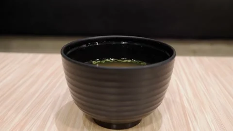 White smoke floating from the broth with spring onions in a black cup on table Stock Footage 134825204