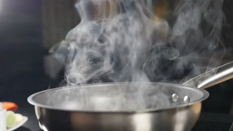 White smoke in slow motion rising above hot frying pan on black background Stock Footage 140299153