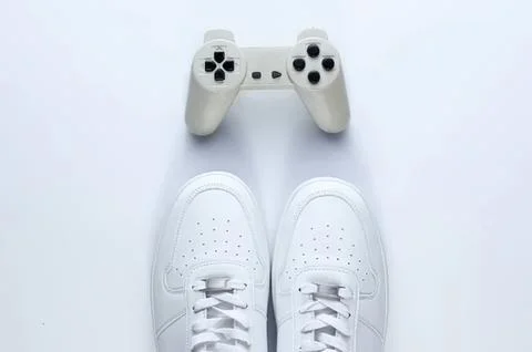 White sneakers and game controller on a white background Stock Photos