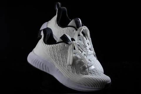 White sneakers resting on a solid black background showcasing modern athletic Foto stock