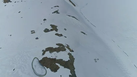 White snow field with some thawed rocky patches near frozen iced Tilicho Lake Stock Footage 124679465